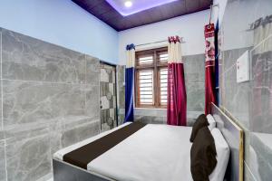 a small bedroom with a bed and a window at Hotel O Dream Guest House in Rudrapur