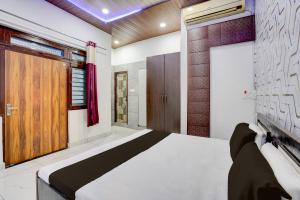 a bedroom with a bed and a wooden door at Hotel O Dream Guest House in Rudrapur +47 photos