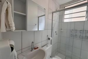 a white bathroom with a sink and a mirror at Apto completo, ar cond e vaga in Ourinhos