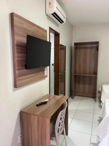 una stanza con una scrivania con una televisione sul muro di Pousada Lagoa Seca a Juazeiro do Norte