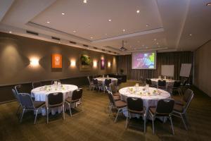 una sala de conferencias con mesas, sillas y una pantalla en Mercure Sydney Parramatta en Sídney