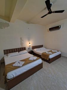 a bedroom with two beds and a ceiling fan at The Fero Hotel in Somnath +11 photos