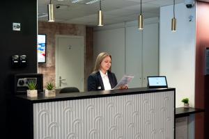 a woman sitting at a counter in an office at Nemea Appart Hotel Quai Victor Tours Centre in Tours