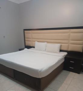 a bed with white sheets and pillows in a room at نوارة المنسك للشقق الفندقية in Abha