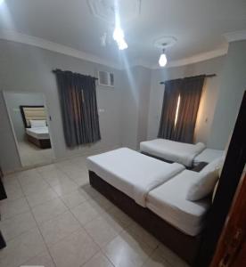 a bedroom with two beds and a mirror at نوارة المنسك للشقق الفندقية in Abha