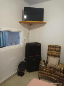una camera con TV a parete e sedia di Cantinho de casa a Votuporanga