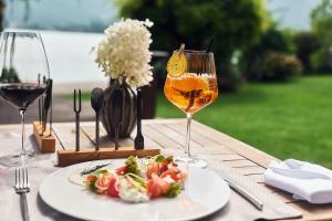 a table with a plate of food and a glass of wine at Hotel Seevilla Wolfgangsee in St. Wolfgang