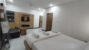 a white bedroom with a bed and a television at Embassy Grand in Jāmb