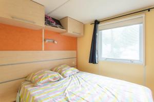 a small bedroom with a bed and a window at mobile-home camping de la truite in Ascarat