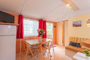 a kitchen and living room with a table and a couch at mobile-home camping de la truite in Ascarat +13 photos
