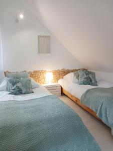 a bedroom with two beds and a lamp on a wall at Eleonor Accommodation in Liszki