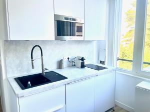 una cucina bianca con un lavello e un forno a microonde di Studio dans la résidence Hermitage a Le Touquet-Paris-Plage Altre 3 foto
