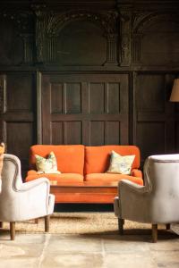 an orange couch in a room with two chairs at Sand Manor in Sidbury +31 photos
