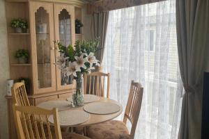 a dining room table with a vase of flowers on it at 2 Bedroom Caravan - Sleeps 6 - Seaside Parking in Kinmel Bay +5 photos