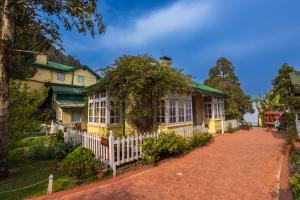 a yellow house with a white fence in front of it at Windamere Hotel - A Colonial Heritage Since 1841 in Darjeeling