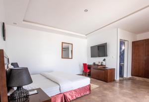 a bedroom with a bed and a desk and a tv at Le Feto 2 in Dakar
