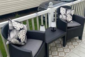 a pair of chairs and a table on a porch at 2 Bedroom Caravan - Sleeps 6 - Seaside Parking in Kinmel Bay