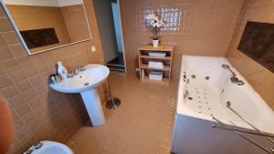 ein Badezimmer mit Badewanne und Waschbecken in der Unterkunft La maison V in Pontebba