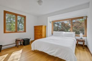 a white bedroom with a large bed and two windows at House Under The Cliff in New Paltz