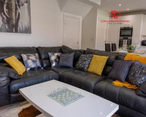 a black leather couch with pillows and a white table at Luxury 5BR House with Jacuzzi plus Gym - 1 BR Garden Self-Contained Suite in Garden -booked separately- in Basildon