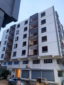 een groot wit gebouw met een auto voor de deur bij Luxury 2BR Near Icon 36 2 AC, 2 TV & City View in Karachi