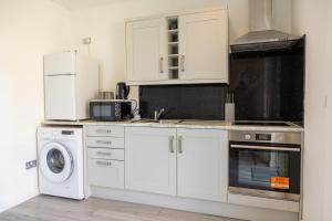 a kitchen with white cabinets and a washer and dryer at Luxury 5BR House with Jacuzzi plus Gym - 1 BR Garden Self-Contained Suite in Garden -booked separately- in Basildon