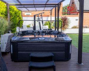 a hot tub on a deck with a table and chairs at Luxury 5BR House with Jacuzzi plus Gym - 1 BR Garden Self-Contained Suite in Garden -booked separately- in Basildon