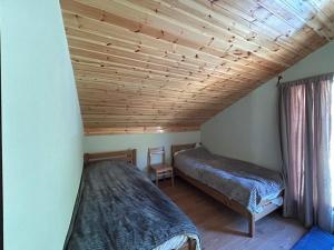 two beds in a room with a wooden ceiling at Panorama Ardoti in Ardoti
