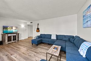 a living room with a blue couch and a tv at Coastal Condo, Water Views, Fishing Dock & 0.6 Miles to Siesta Beach in Siesta Key