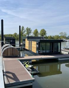 Una casa está sentada en un muelle en el agua. en De Maasterp - Woonboot 2, en Montfort