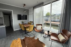 Una sala de estar con una mesa y sillas y una gran ventana. en De Maasterp - Woonboot 2, en Montfort