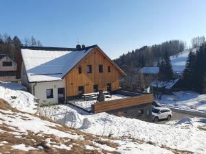 un grande fienile in legno con neve per terra di Chalet Lucie a Bedřichov