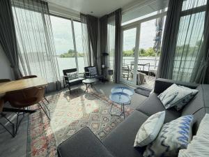 a living room with a couch and a view of the water at De Maasterp - Woonboot 5 in Montfort