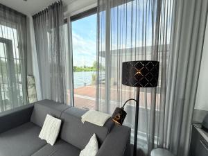 a living room with a couch and a large window at De Maasterp - Watervillage 21 in Ohé en Laak
