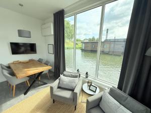 a living room with a table and a large window at De Maasterp - Woonboot 16 in Montfort