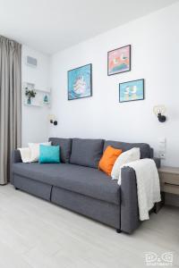 a living room with a gray couch with colorful pillows at Mewa Aquamarina Onyx D&D Apartments in Międzyzdroje