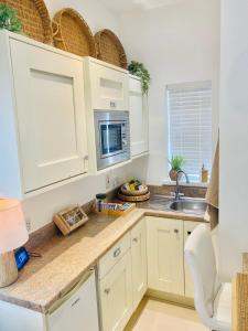a kitchen with white cabinets and a sink and a microwave at 1 Bed Flat - Sleeps 2 - Pets - Parking - Garden in Eglinton