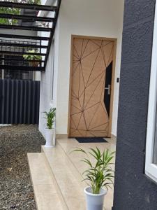 uma porta para uma casa com dois vasos de plantas em The Tea Leaf Munnar em Anachal