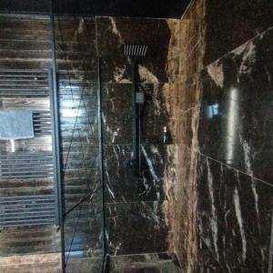 a shower in a bathroom with a stone wall at Casuta D&M in Cisnădie