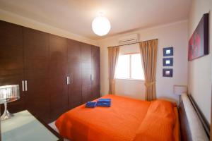 a bedroom with an orange bed and a window at Ascot By The Sea in St Paul's Bay