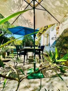 a table and chairs with an umbrella in the sand at T2 cosy avec jardin privé et terrasses au calme in Cabriès +2 photos