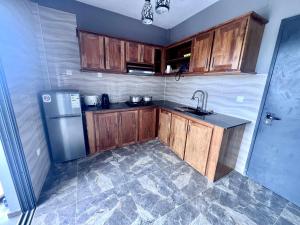 a kitchen with wooden cabinets and a stainless steel refrigerator at Appart Nouvelle Ville Toamasina in Toamasina +5 photos