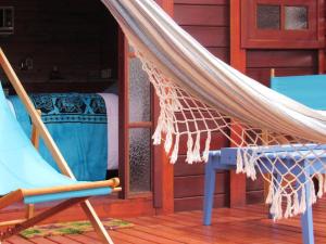 a hammock on a porch with a chair and a bed at Posada Las Maravillas in Punta Del Diablo