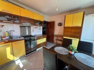 a kitchen with yellow cabinets and a table with chairs at Casa Alexana in Gura Humorului
