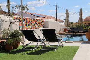two chairs sitting on the grass next to a pool at Casa do Campinho B&B boutique country house in Reguengos de Monsaraz