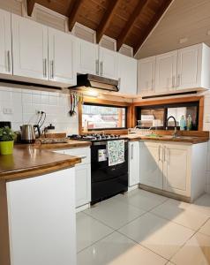 Una cocina con gabinetes blancos y una estufa negra. en Cabañas Alto del Bosque, en Coñaripe
