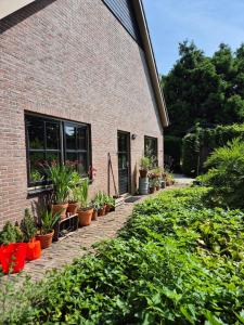 a brick building with potted plants in front of it at Vakantiehuis Joghmanstuin in Kapel-Avezaath +8 photos