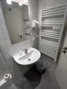 a white bathroom with a sink and a mirror at Hotel Haus Schwan Köln in Cologne
