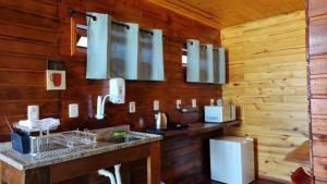 a kitchen with wooden walls and a counter with a sink at Posada Las Maravillas in Punta Del Diablo