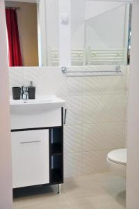 a white bathroom with a sink and a toilet at HOGOR Apartments in Sibiu